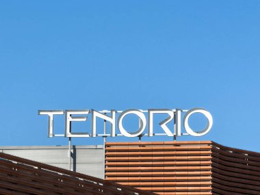 Wolfsberg, Avusturya - 19 Eylül 2025: TENORIO tabelası, modern mimari özellikleri vurgulayan, parlak mavi gökyüzünün altındaki parlak bir binada sergilendi