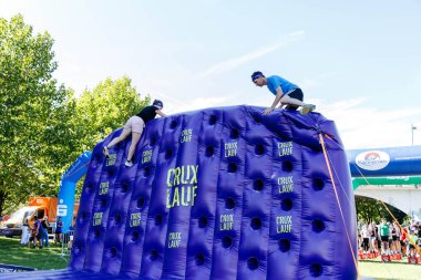 Villach, Avusturya - 20 Eylül 2025: Sporcular CRUX 'ta coşkulu kalabalık ve açık mavi gökyüzü ile çevrili şişme duvara tırmanıyorlar