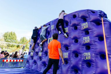 Villach, Avusturya - 20 Eylül 2025: Sporcular canlı bir atmosferde güç ve kararlılığını gösteren CRUX etkinliğinde renkli şişme duvara tırmandılar