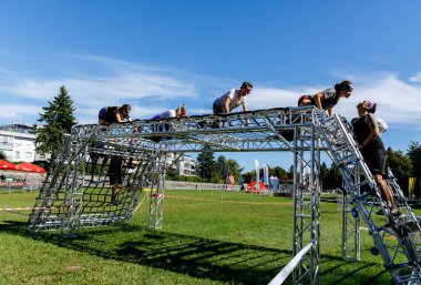 Villach, Avusturya - 20 Eylül 2025: Sporcular bir açık hava yarışmasında takım çalışması ve fiziksel güç sergileyerek engelli bir saha yapısında yol alıyorlar