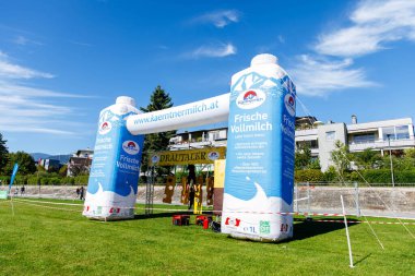 Villach, Avusturya - 20 Eylül 2025: Açık hava etkinliklerinde süt ürünleri için şişirilebilir kemer, açık mavi gökyüzü ile canlı bir parkta taze sütü teşvik etmek