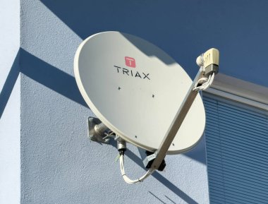 Bleiburg, Avusturya - 19 Eylül 2025: Triax uydu anteni mavi duvara kurulmuş, iletişim ve eğlence için gelişmiş teknolojiyi vurguluyor