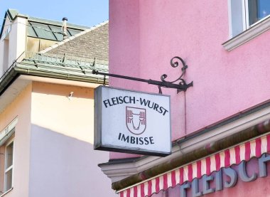 Bleiburg, Avusturya - 19 Eylül 2025: Pembe bir duvarda Fleisch-Wurst Imbisse imzası, hareketli sokak atmosferine karakter katıyor