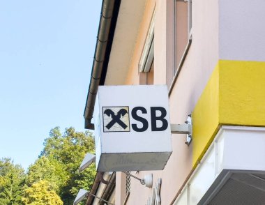 Bleiburg, Avusturya - 19 Eylül 2025: SB marka tabela, ağaçlarla çevrili, kentsel ticari atmosferi vurgulayan bir binada çapraz araçlar sergiliyor