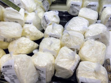 Bleiburg, Avusturya - 19 Eylül 2025: Markette paketlenmiş peynir blokları, mutfak uygulamaları için farklı boyutları ve dokuları vurguluyor