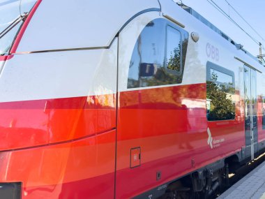 Bleiburg, Avusturya - 19 Eylül 2025: OBB tren çarpıcı kırmızı ve gümüş tasarım özellikleri, markalaşma veya mesajlaşma için geniş bir kopya alanı ile istasyonda park