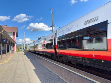 Sankt Veit Ad Glan, Avusturya - 17 Eylül 2025: Canlı renkler ve açık gökyüzü ile istasyona yaklaşan şehir jeti etkin seyahat