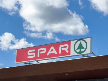 Sankt Veit Ad Glan, Avusturya - 17 Eylül 2025: SPAR mağaza levhası açık bir şekilde beyaz bulutlu canlı mavi gökyüzüne karşı sergilenerek, davetkar bir alışveriş ortamı yarattı