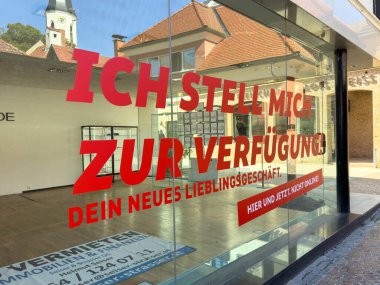 Sankt Veit Ad Glan, Avusturya - 17 Eylül 2025: Mağaza vitrininde çarpıcı kırmızı harfler, modern tasarım unsurları sergileniyor ve atmosfer davet ediliyor