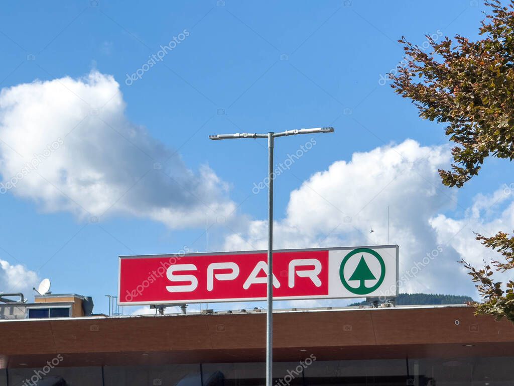Sankt Veit Ad Glan, Austria - September 17, 2025: SPAR supermarket logo prominently displayed against a clear blue sky with clouds, highlighting the retail atmosphere