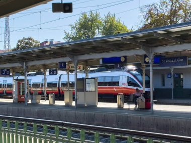 Sankt Veit Ad Glan, Avusturya - 17 Eylül 2025: St. Veit an der Glan istasyonunda canlı renkler ve yakınlarda bekleyen yolcularla modern tren