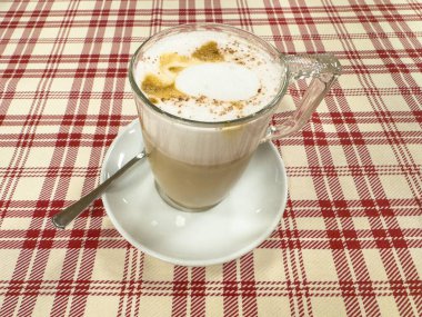 Süt köpüğü ve tarçınlı kareli masada nefis kapuçino..