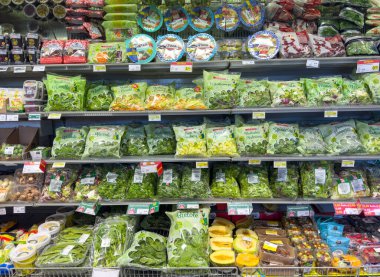 Gemona, İtalya - 24 Eylül 2025: Paketlenmiş yeşiller ve taze sebzeler süpermarket raflarında düzenli bir şekilde düzenlenerek, sağlık bilincine sahip tüketiciler için renkli bir seçim sunuluyor