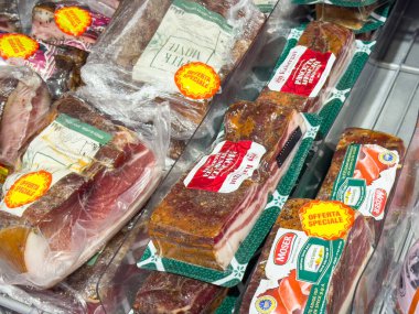 Gemona, İtalya - 24 Eylül 2025: Markette paketlenmiş etler, çeşitli markalar ve renkli etiketler, taze şarküteri seçimleri