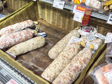 Gemona, İtalya - 24 Eylül 2025: Çeşit çeşit pişirilmiş etler, kaliteli ve gelenekleri ön plana çıkaran bir gurme marketinde hasır bir sepette güzelce düzenlenmiştir