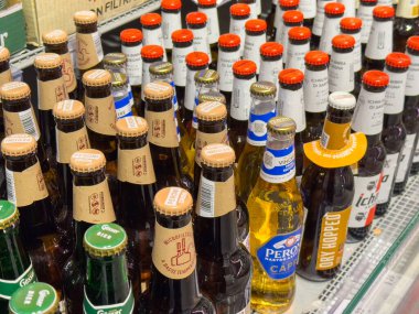 Gemona, İtalya - 24 Eylül 2025: Perakende mağazasında çeşitli markalar ve içecek tanıtımı için canlı renklerin vurgulandığı çeşitli bira şişeleri