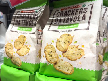 Gemona, İtalya - 24 Eylül 2025: Delspar krakerleri bir süpermarket rafında güzelce paketlenmiştir, sağlıklı atıştırmalık cazibeleri ve davetkar dokuları vurgulanmıştır.