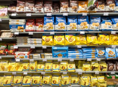 Gemona, İtalya - 24 Eylül 2025: Süpermarket rafında çeşitli marka ve lezzetlerin yer aldığı canlı kurabiye ve abur cubur gösterisi