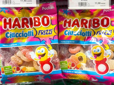 Gemona, İtalya - 24 Eylül 2025: Haribo Ciucciotti Frizzi şeker paketleri parlak renkler ve eğlenceli grafikler içeren bir mağaza rafında belirgin bir şekilde sergilenmektedir