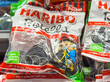 Gemona, İtalya - 24 Eylül 2025: Haribo Rotella şeker paketi renkli tasarımı ve lezzetli tatlılar için cazip markaları vurgulayan neşeli bir çocuğu scooter 'da sergiliyor