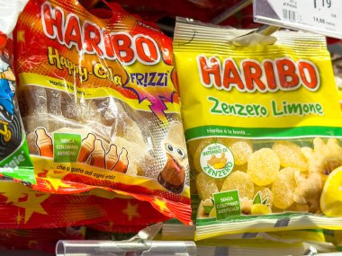 Gemona, İtalya - 24 Eylül 2025: Haribo şeker paketleri Mutlu Kola ve Zenzero Limon aromalarını renkli bir mağaza rafında sergiliyor, şeker meraklılarını bu zevkli ikramda bulunmaya davet ediyor