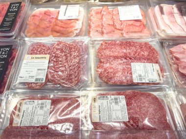 Gemona, İtalya - 24 Eylül 2025: Markette salam, jambon ve canlı renklerde tavuk dilimlerinin yer aldığı çeşitli mezeler