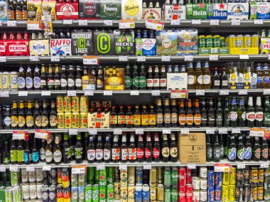 Gemona, İtalya - 24 Eylül 2025: Süpermarket raflarında düzenlenmiş çeşitli bira şişeleri, farklı marka ve ambalaj stillerini vurguluyor