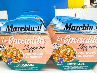 Gemona, İtalya - 24 Eylül 2025: Mareblu ton balığı salatası ambalajı bakkalda belirgin bir şekilde sergilenmekte, taze malzemelerin altını çizmekte ve sağlık bilincine sahip tüketiciler için çekici bir tasarım ortaya koymaktadır