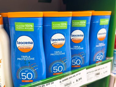 Gemona, İtalya - 24 Eylül 2025: Parlak mavi ambalaj ve çevre dostu tasarımı vurgulayan, perakende rafında SPF 50 ile düzenlenmiş Leocrema güneş kremi şişeleri