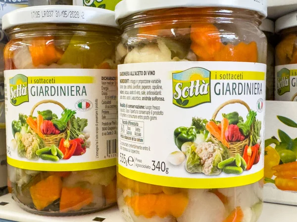 Gemona, İtalya - 24 Eylül 2025: Sott 'it Giardiniera turşulu sebze kavanozları bir rafa dizilir, renkli içerikleri ve çekici ambalajları vurgulanır