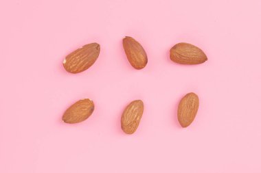 Üstten görünüm badem pembe arka plan, badem desenli arka plan ayarlayın. Fındık bileşimi. Dekorasyon, sağlıklı beslenme ve gıda arka plan hakkında kavramları. Düz yatıyordu, en iyi görünüm. En az kavramı.
