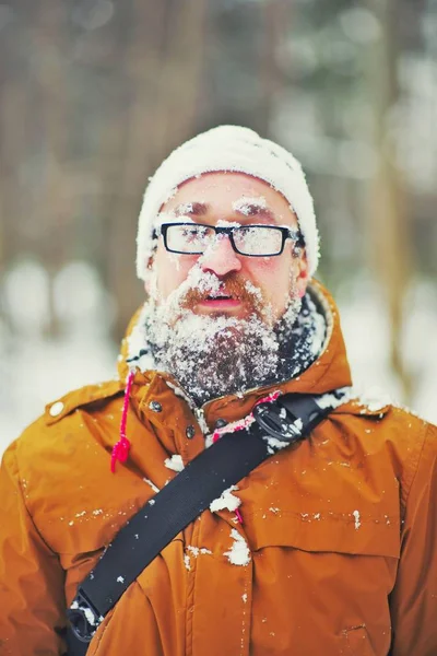 Mutlu genç sakallı adam gün batımında kış ormandaki soğuk havalarda closeup portresi. Eğlenceli adam gülümsüyor. Yüz, sakal, bıyık ve buğulu, gözlük frost ile kaplı.