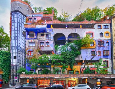 Vienna, Avusturya - 1 Ekim 2018: Hundertwasser Evi, Hundertwasserhaus - konut, fikir ve Avusturyalı ressam Friedensreich Hundertwasser kavramı. Ağaçlar, sonbahar büyüyen ile renkli cephe