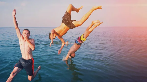 Young people jumping inside ocean in summer excursion day. Happy — Stock Photo, Image