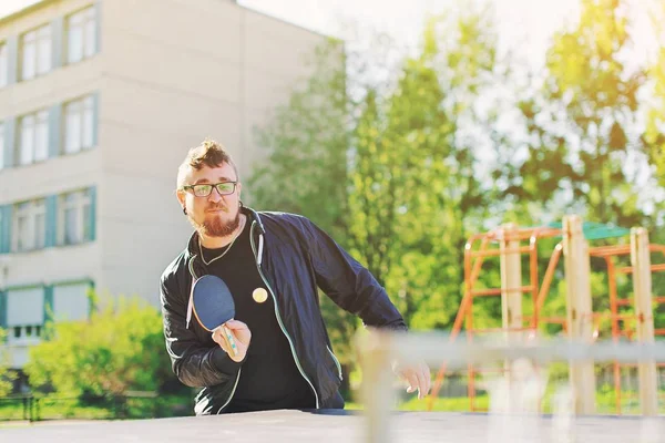 Happy young man playing ping pong table tennis with ball and pad