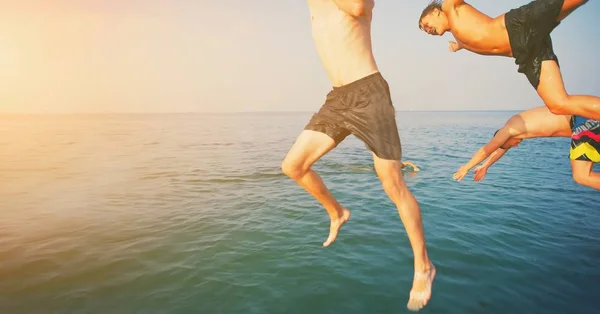 Skupina šťastných šílenských lidí, kteří se baví skákat v mořské vodě z lodi. Přátelé skáčou ve vzduchu na slunné letní párty u potápěčských svátků. Cestovní dovolená, přátelství, koncepce svátků mládeže. — Stock fotografie