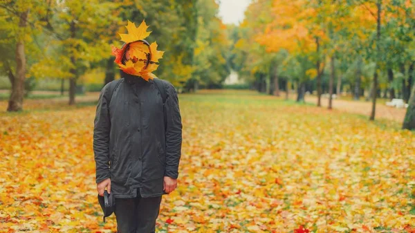 Extraño hombre hipster en chaqueta parka negra con hojas de otoño en fa — Foto de Stock