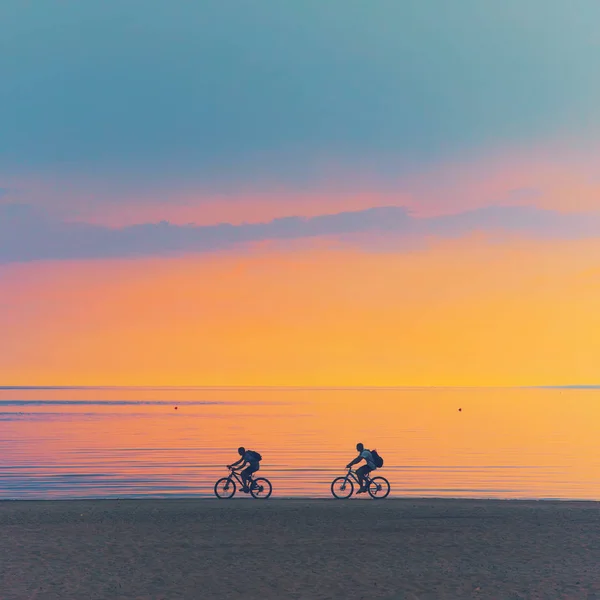 Rowerzysta sylwetka jazda wzdłuż plaży o zachodzie słońca na rowerze sportowy com — Zdjęcie stockowe