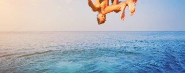 Genç adam Sunset 'te mavi su Okyanusu 'Na atlayıp Cliff 'e atlıyor. Hareket