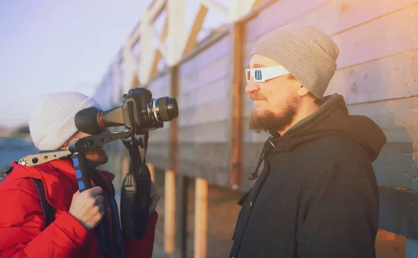 Actor in front of camera on outdoor location. Videographer with