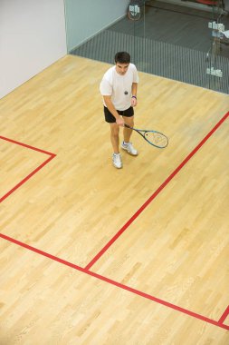 Genç adam squash oynuyor.