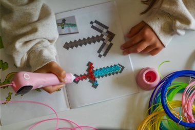 Pembe 3D kalem. Çocuk erimiş plastikle bir kılıç çekiyor. Bilim, yeni teknolojiler, çocuk eğitimi. Yüksek kalite fotoğraf