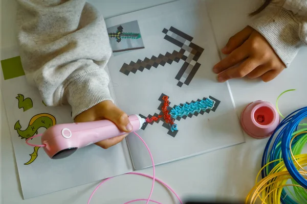 Pembe 3D kalem. Çocuk erimiş plastikle bir kılıç çekiyor. Bilim, yeni teknolojiler, çocuk eğitimi. Yüksek kalite fotoğraf