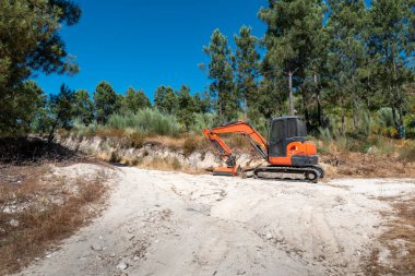 Mini kazıcı kırsal bir toprak yolun kesiştiği yolu temizliyor.