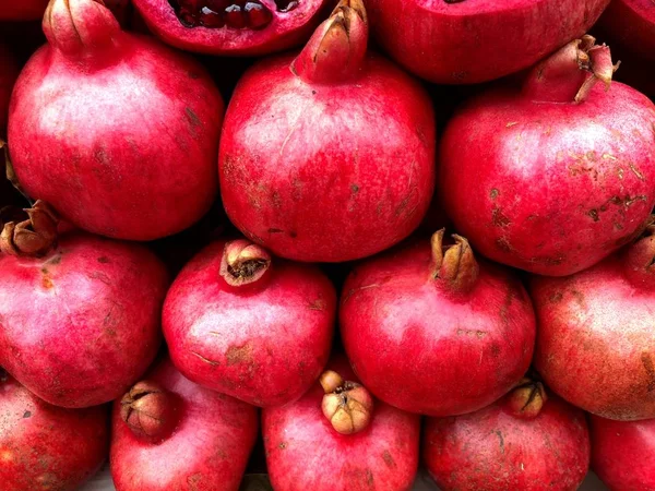 Sliced juicy bright red pomegranates. Fragment from a fruit and vegetable shop.