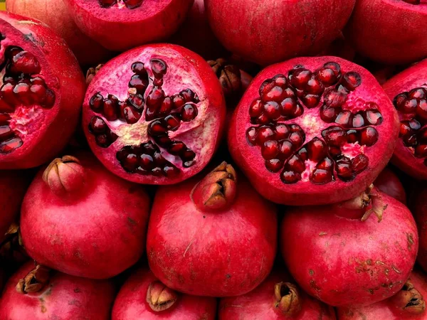 Sliced juicy bright red pomegranates. Fragment from a fruit and vegetable shop.