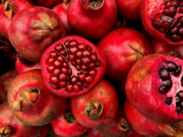 Sliced juicy bright red pomegranates. Fragment from a fruit and vegetable shop.