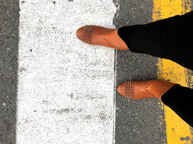 Yaya geçidi. Sarı ve beyaz renkler kaldırım ve kadın bacakları