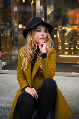 Zeytin ceket ve siyah geniş ekledi şapka giyen genç güzel bir moda bayan açık portresi. Modeli bir kenara arıyorum. Kadın moda kavramı. Şehir bir yaşam tarzı. Yakın çekim.