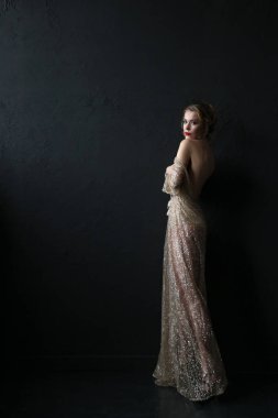 Siyah zemin üzerine altın kolye ile şeffaf elbiseli seksi sarışın